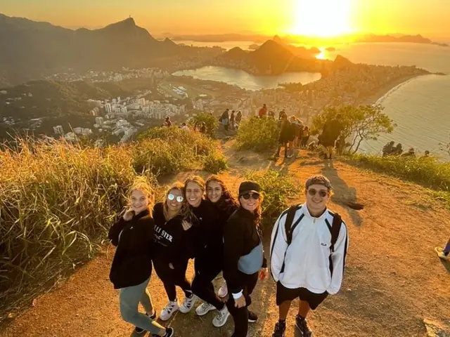 Travelers gathering above Rio at sunrise after a mountain hike